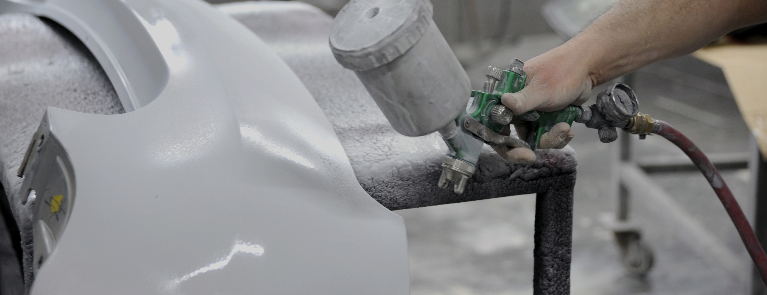 Aplicação de revestimento automóvel com pistola de pintura em ambiente industrial, ilustrando soluções técnicas testadas diretamente na linha de produção.